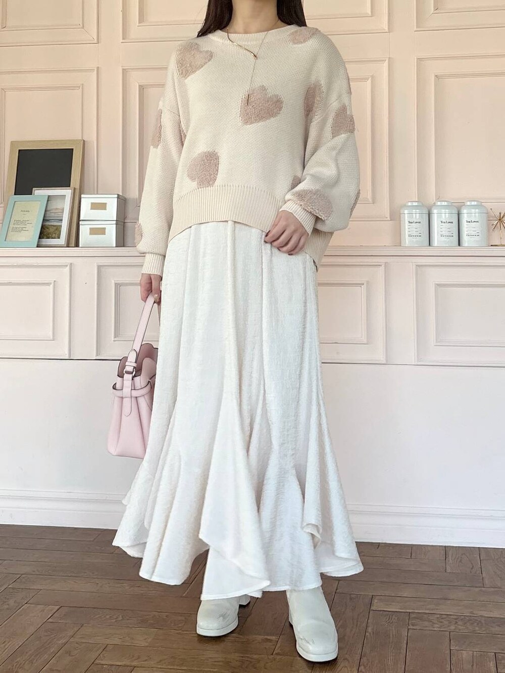 ピンク系のショルダーバッグ、ホワイト系のブーツ、ホワイト系のスカートを着用したレディースの冬コーディネートの4枚目の写真