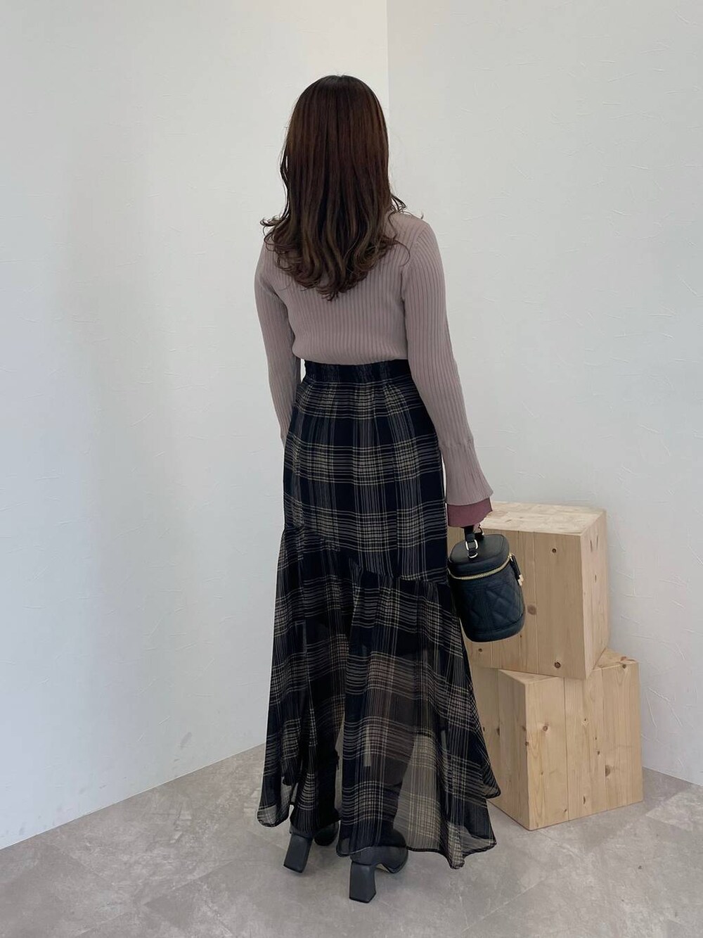 グレー系のブーツ、ブラック系のショルダーバッグ、ブラウン系のニット/セーターを着用したレディースの秋コーディネートの2枚目の写真