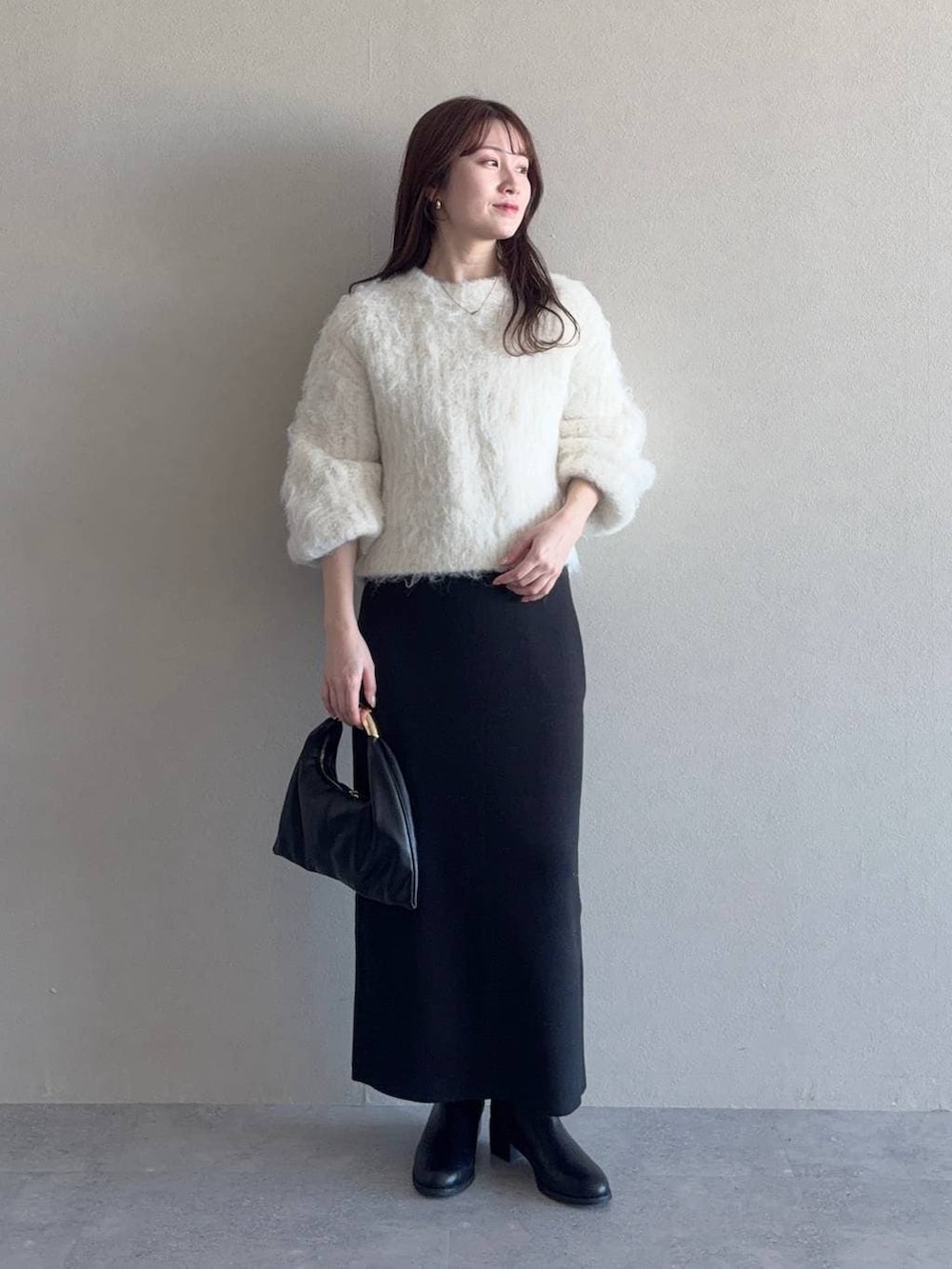 ブラック系のスカート、ブラック系のハンドバッグ、ホワイト系のステンカラーコートを着用したレディースの冬コーディネートの3枚目の写真