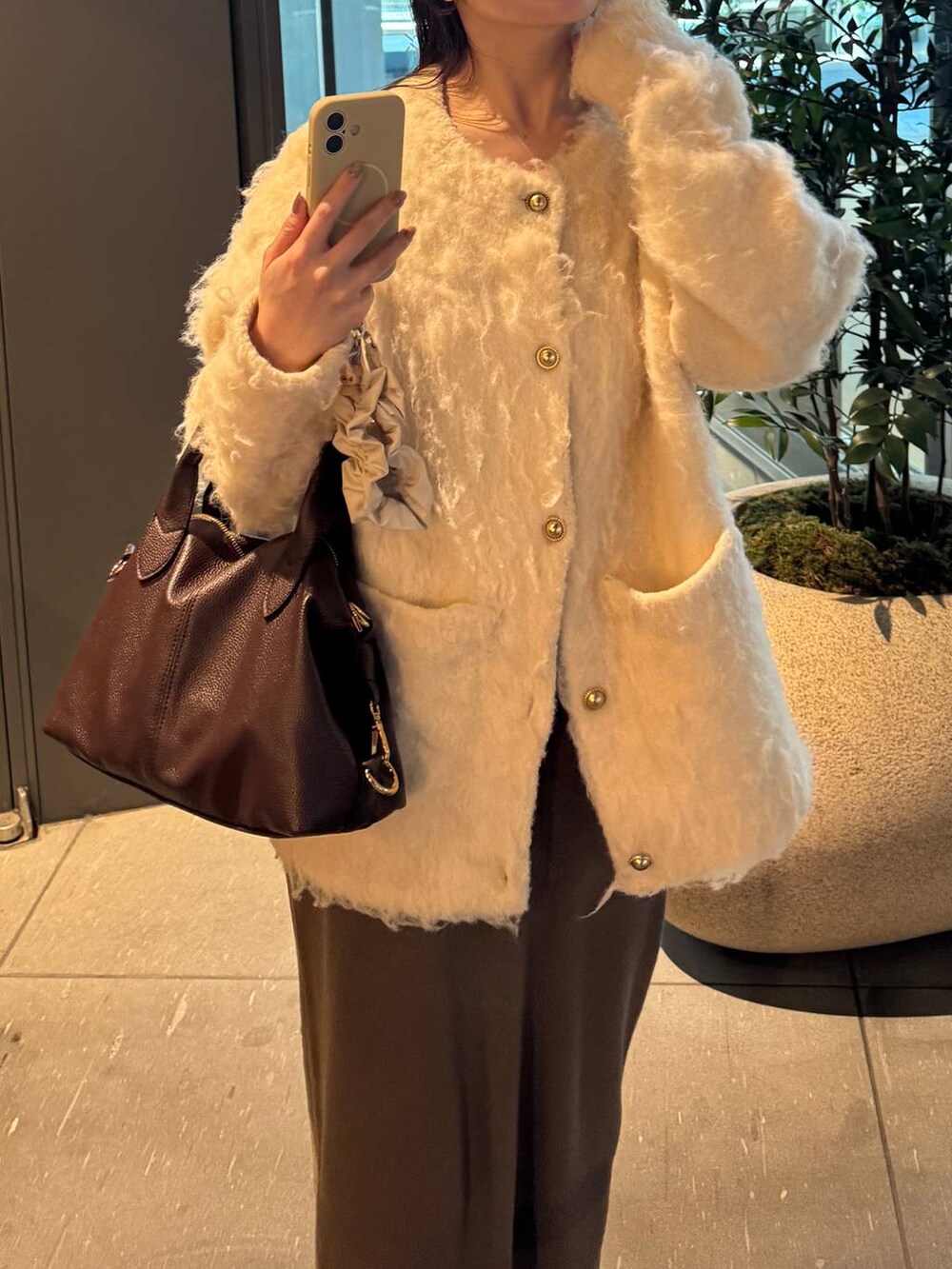 ブラウン系のボストンバッグ、ブラウン系のスカート、ホワイト系のカーディガン/ボレロを着用したレディースの冬コーディネートの2枚目の写真