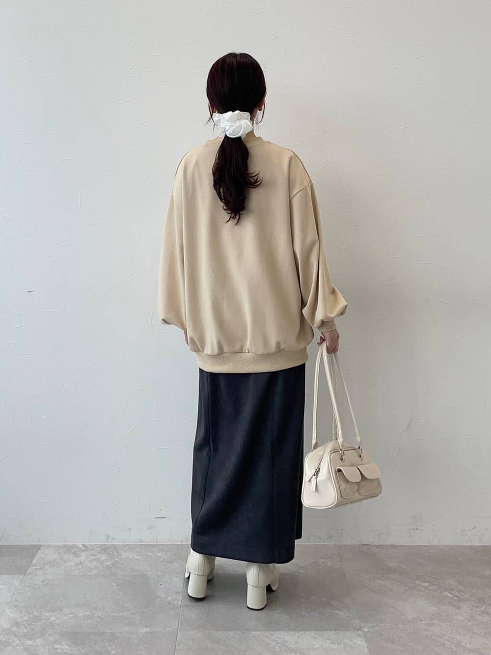 ホワイト系のブーツ、グレー系のスカート、ベージュ系のスウェットを着用したレディースの秋コーディネートの2枚目の写真