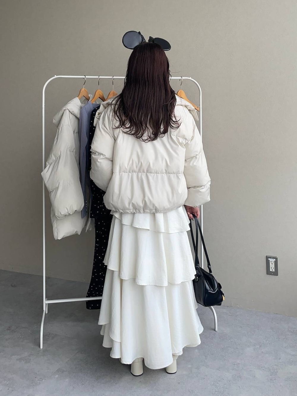 ホワイト系のブーツ、ホワイト系のスカート、ブラック系のハンドバッグを着用したレディースの秋コーディネートの2枚目の写真