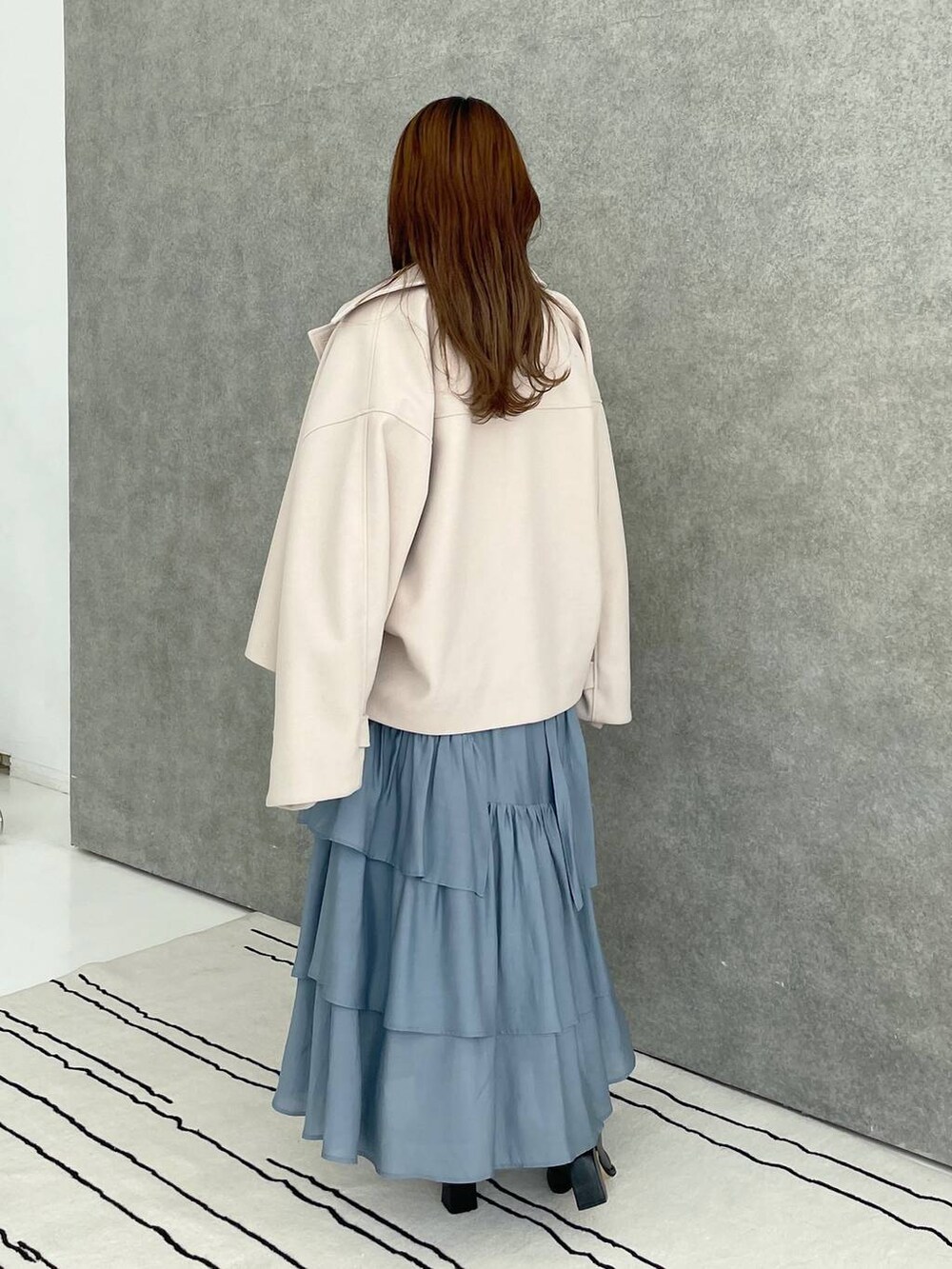 ホワイト系のその他アウター、ブラック系のブーツ、ブルー系のスカートを着用したレディースの秋コーディネートの2枚目の写真