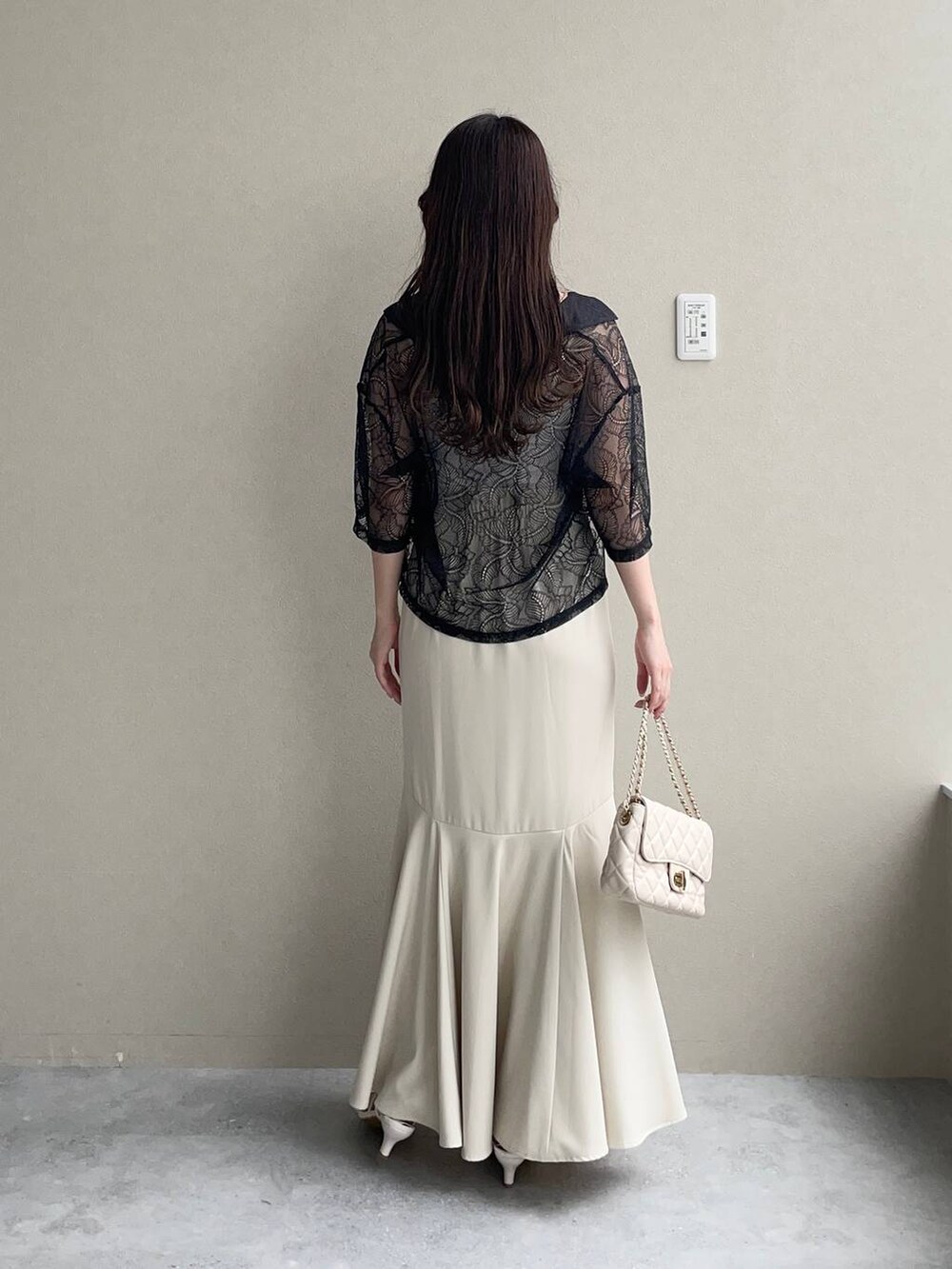 ホワイト系のショルダーバッグ、ホワイト系のサンダル、ブラック系のシャツ/ブラウスを着用したレディースの夏コーディネートの2枚目の写真