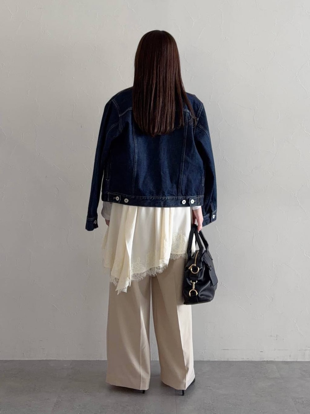 ホワイト系のTシャツ/カットソー、ブラック系のボストンバッグ、ブルー系のデニムジャケットを着用したレディースの冬コーディネートの2枚目の写真