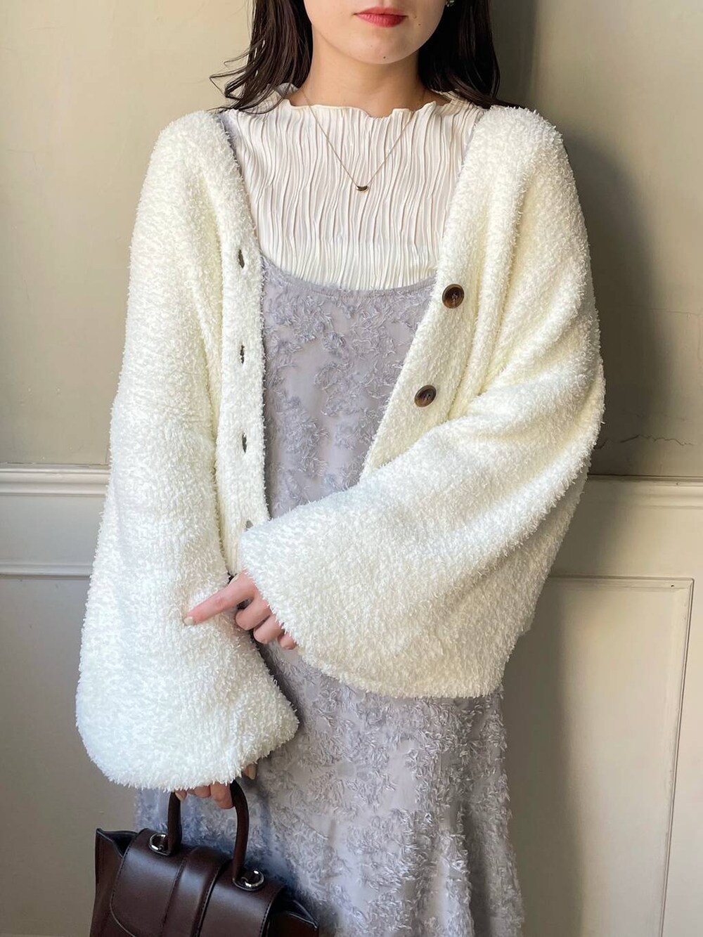 ブラウン系のハンドバッグ、ホワイト系のブーツ、ホワイト系のTシャツ/カットソーを着用したレディースの秋コーディネートの3枚目の写真