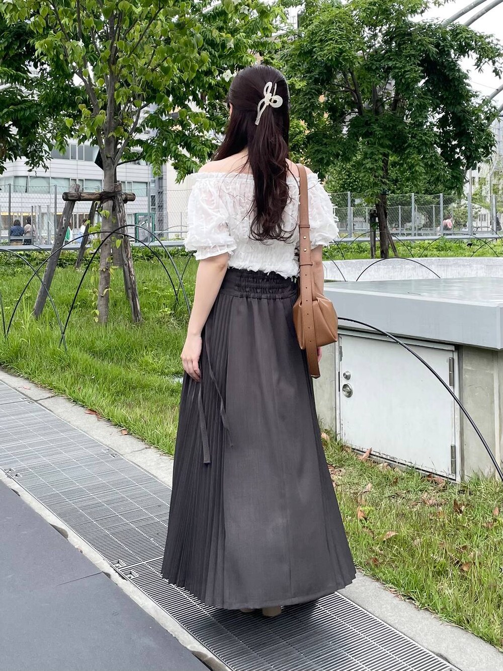 ブラウン系のショルダーバッグ、グレー系のスカート、ホワイト系のシャツ/ブラウスを着用したレディースの夏コーディネートの2枚目の写真