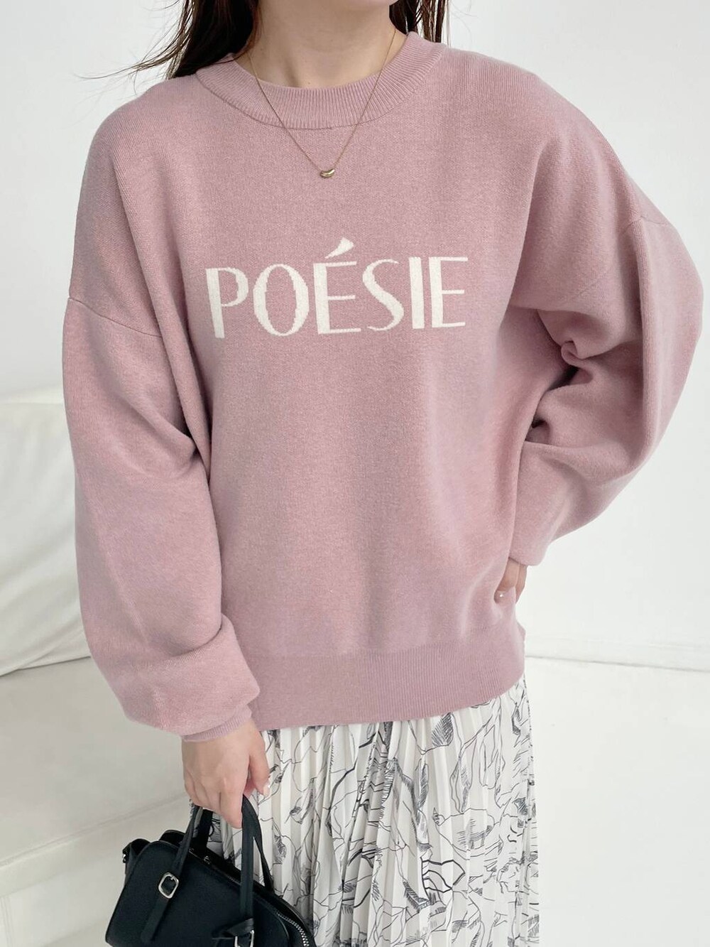 ブラック系のボストンバッグ、ブラック系のブーツ、ピンク系のニット/セーターを着用したレディースの秋コーディネートの3枚目の写真