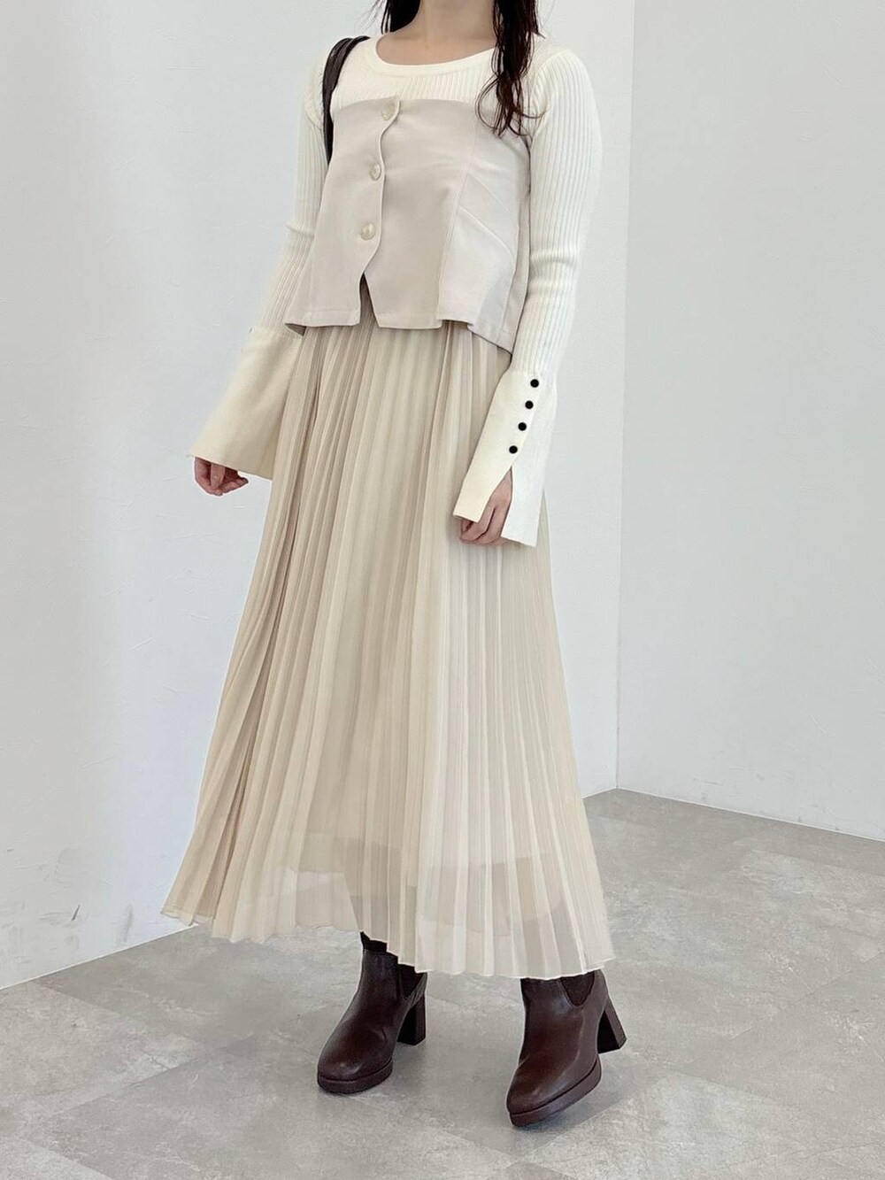 ブラウン系のブーツ、ホワイト系のニット/セーター、ブラウン系のハンドバッグを着用したレディースの冬コーディネートの4枚目の写真