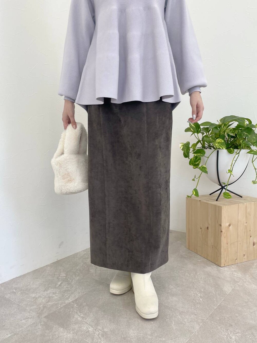 ブラウン系のスカート、ホワイト系のブーツ、ホワイト系のハンドバッグを着用したレディースの冬コーディネートの4枚目の写真