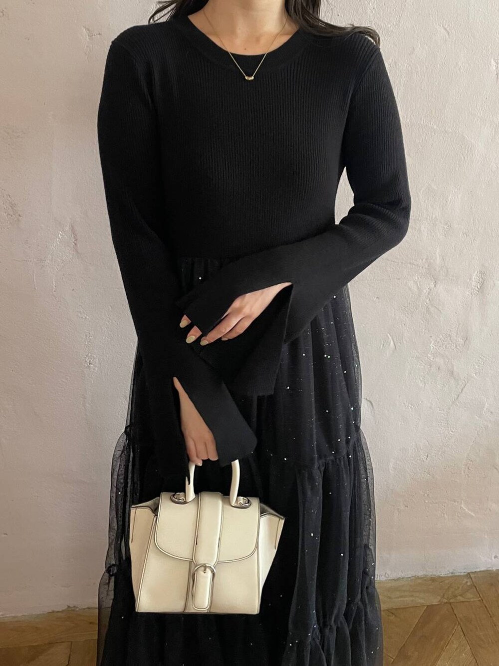 ホワイト系のハンドバッグ、ブラック系のブーツ、ブラック系のワンピースを着用したレディースの秋コーディネートの4枚目の写真