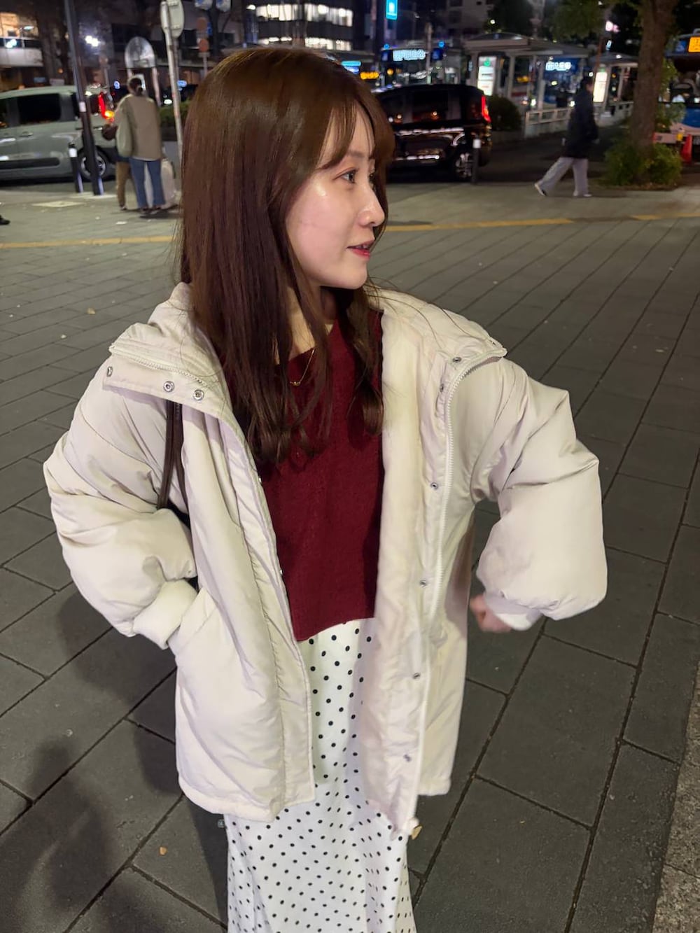 レッド系のニット/セーター、ホワイト系のブルゾン、ホワイト系のスカートを着用したレディースの冬コーディネートの3枚目の写真