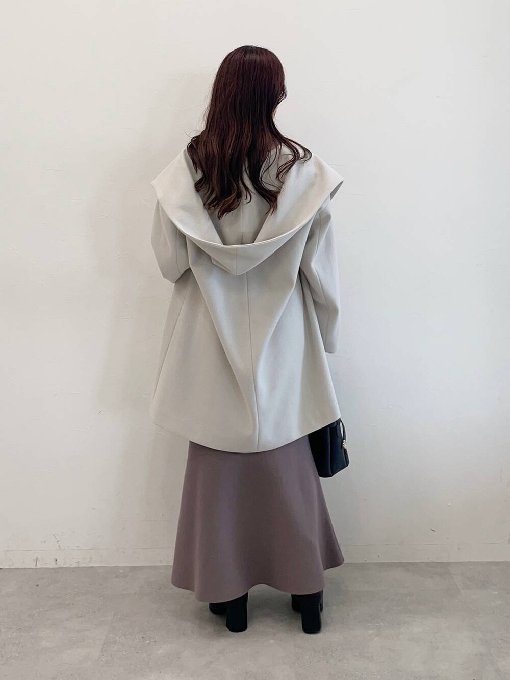 ホワイト系のノーカラーコート、ブラック系のショルダーバッグ、ブラウン系のワンピースを着用したレディースの秋コーディネートの2枚目の写真