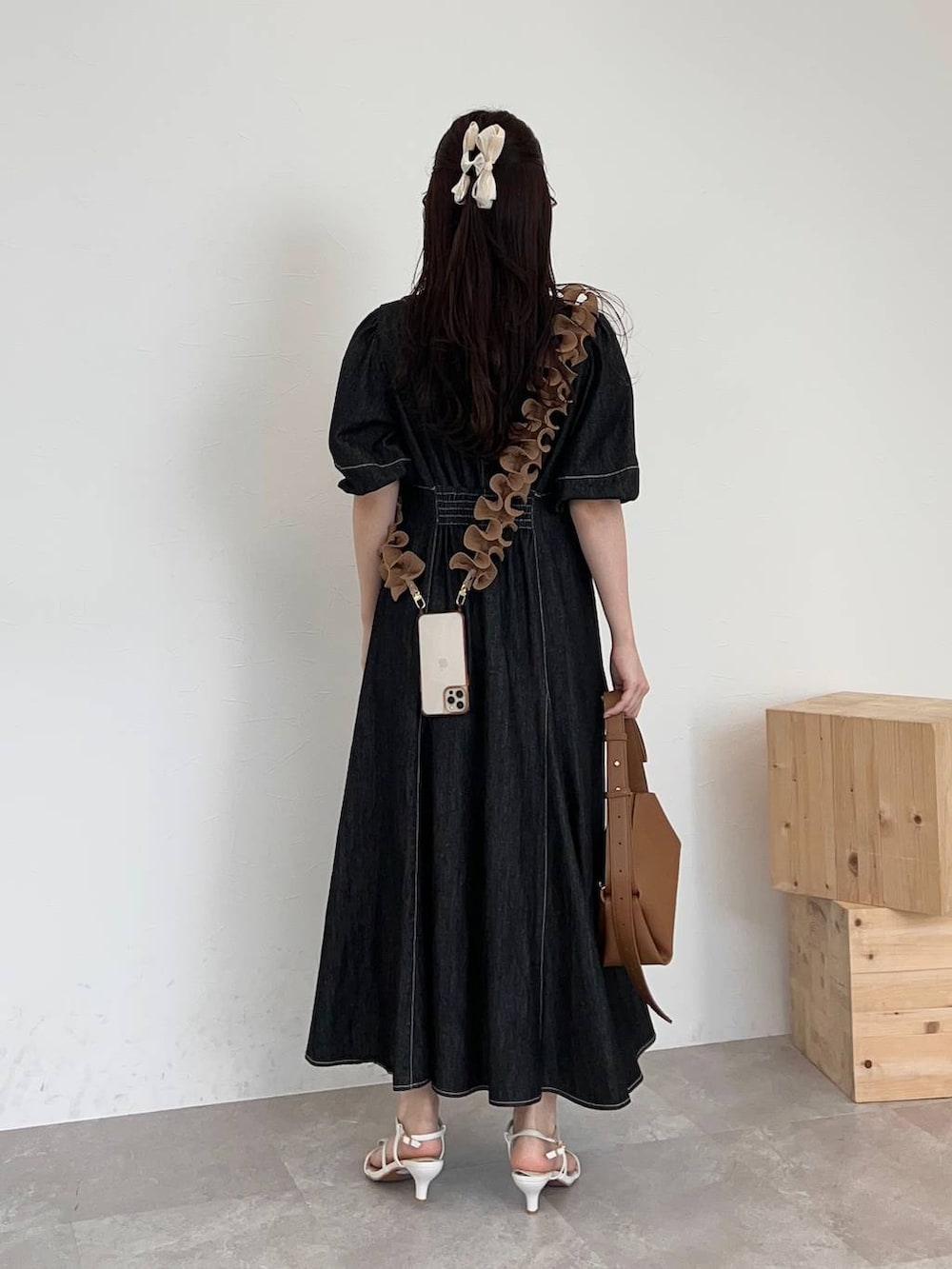 ブラウン系のショルダーバッグ、ブラック系のワンピース、ホワイト系のサンダルを着用したレディースの春コーディネートの2枚目の写真