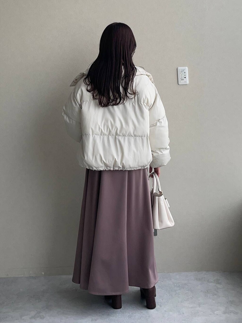 ブラウン系のブーツ、ベージュ系のニット/セーター、ホワイト系のブルゾンを着用したレディースの冬コーディネートの2枚目の写真