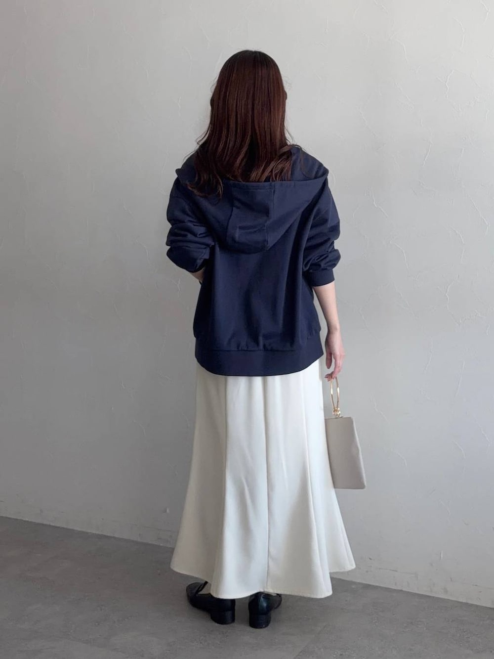 ブラック系のローファー、ブルー系のパーカー、ホワイト系のスカートを着用したレディースの冬コーディネートの2枚目の写真