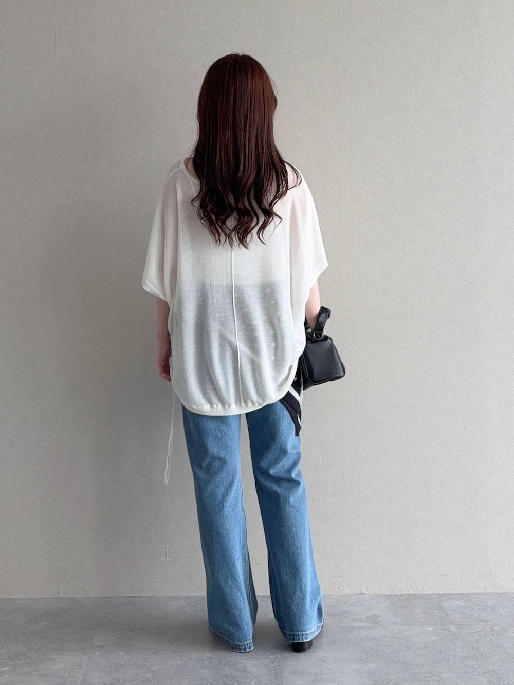 ブルー系のデニムパンツ、ホワイト系のニット/セーター、ブラック系のサンダルを着用したレディースの夏コーディネートの2枚目の写真