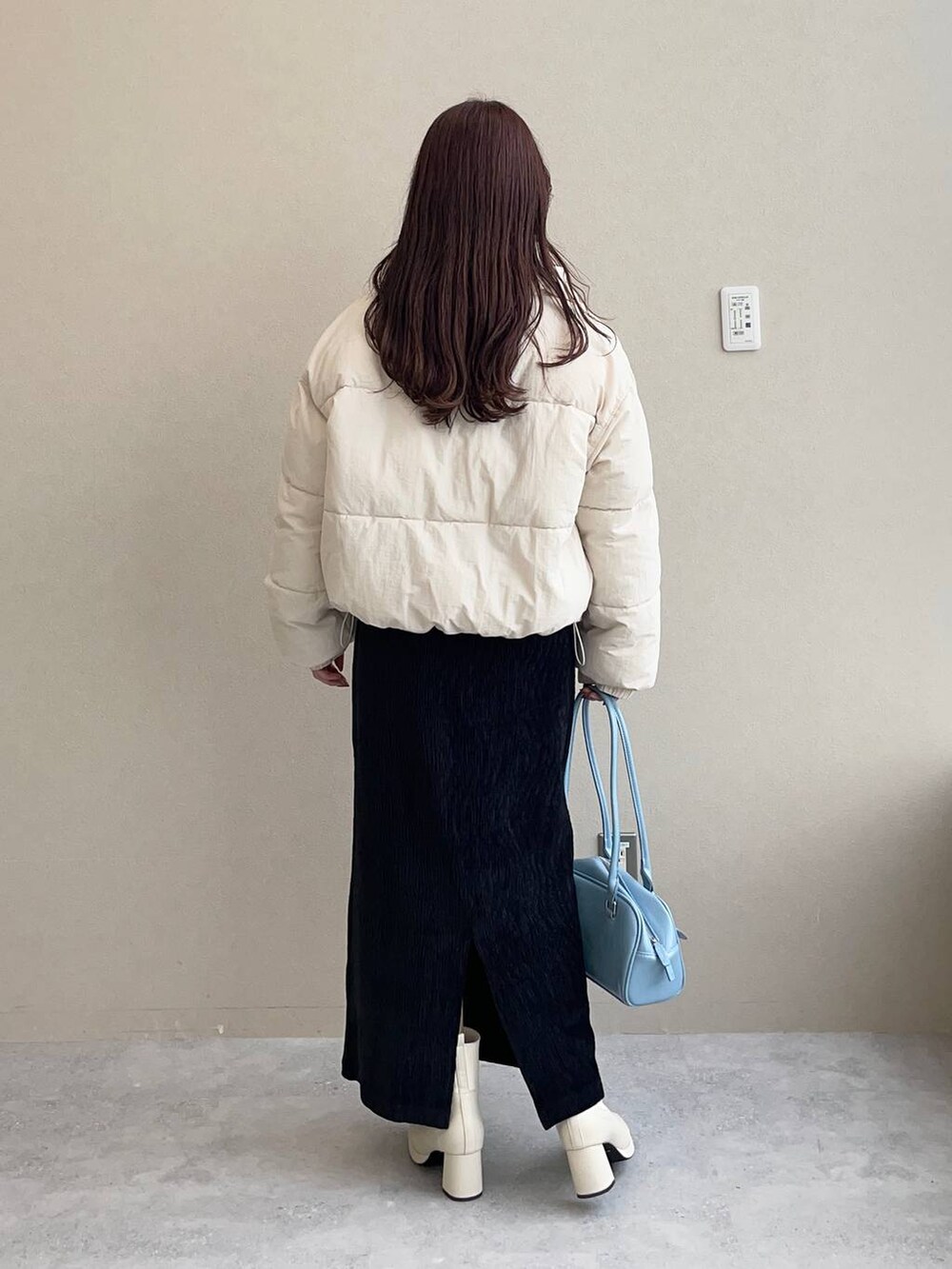 ホワイト系のブルゾン、ホワイト系のブーツ、ブラック系のスカートを着用したレディースの秋コーディネートの2枚目の写真