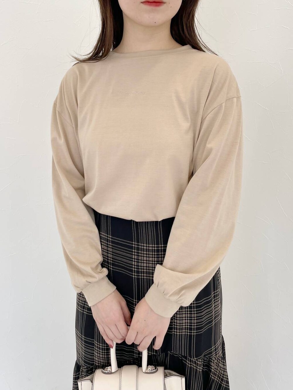 ホワイト系のハンドバッグ、ブラック系のブーツ、ブラック系のスカートを着用したレディースの秋コーディネートの3枚目の写真