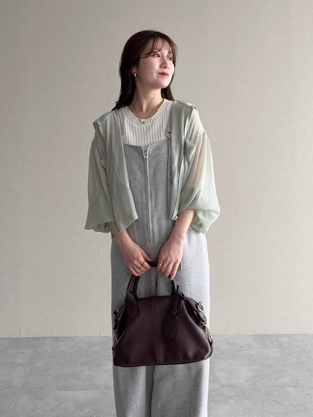 グリーン系のパーカー、ブラウン系のボストンバッグ、ブラウン系のサンダルを着用したレディースの春コーディネートの3枚目の写真