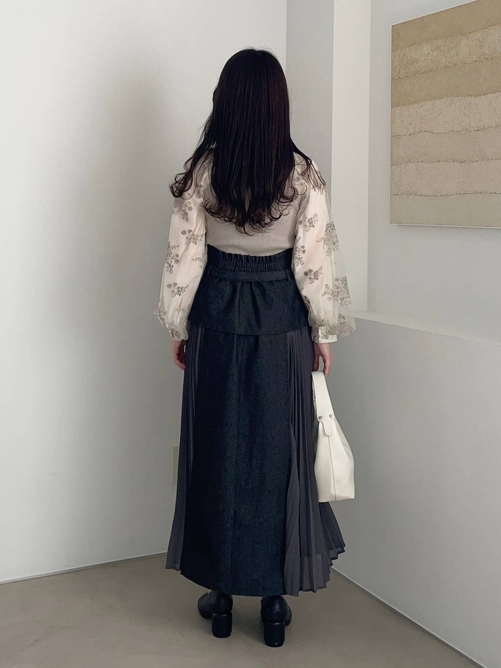 ブラック系のパンプス、ブラック系のスカート、ホワイト系のニット/セーターを着用したレディースの春コーディネートの2枚目の写真