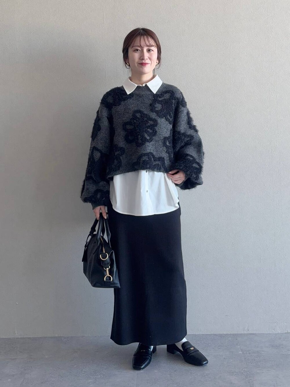 グレー系のニット/セーター、ブラック系のボストンバッグ、ブラック系のスカートを着用したレディースの冬コーディネートの4枚目の写真