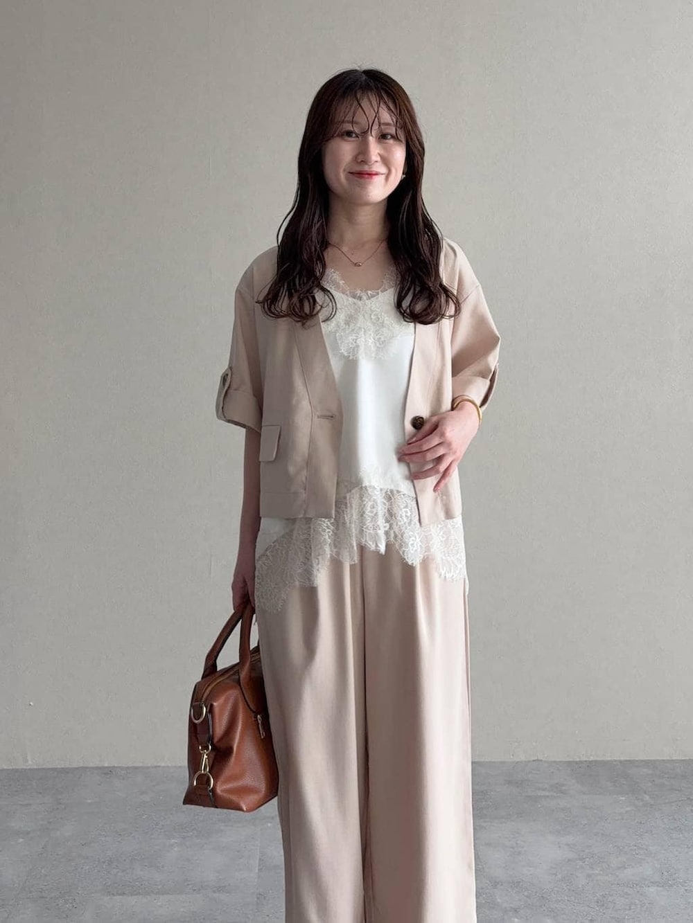 ブラウン系のボストンバッグ、ブラウン系のサンダル、ホワイト系のキャミソールを着用したレディースの春コーディネートの3枚目の写真