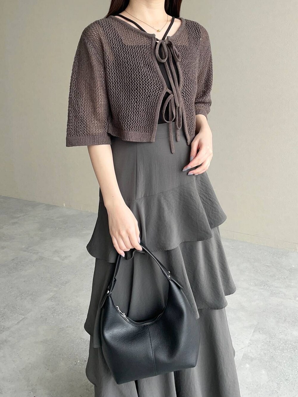 グレー系のスカート、グレー系のカーディガン/ボレロ、ブラック系のショルダーバッグを着用したレディースの春コーディネートの3枚目の写真