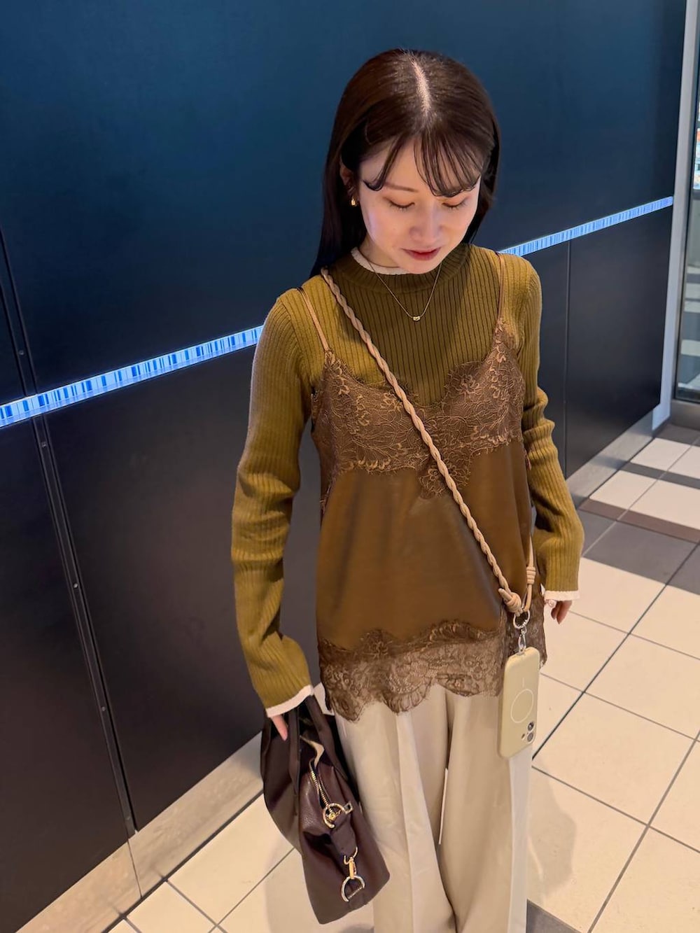 ブラウン系のボストンバッグ、ホワイト系のスラックス、ブラウン系のニット/セーターを着用したレディースの春コーディネートの3枚目の写真