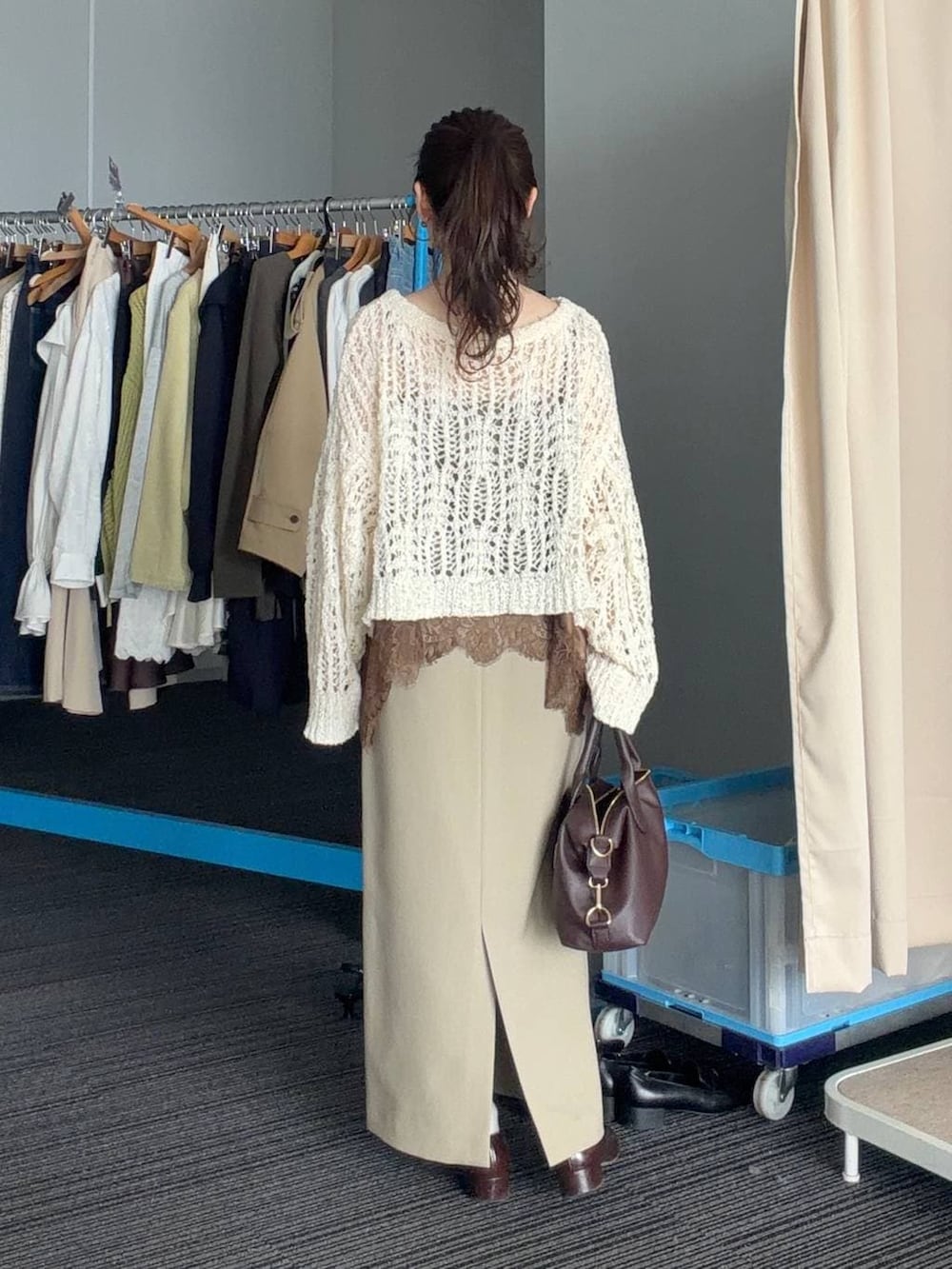 ブラウン系のボストンバッグ、ベージュ系のスカート、ブラウン系のブルゾンを着用したレディースの春コーディネートの4枚目の写真