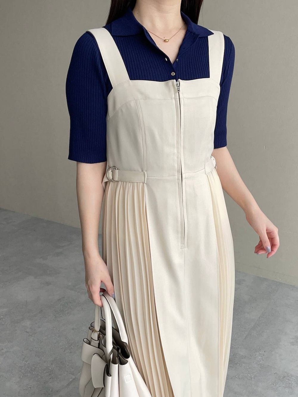 ホワイト系のショルダーバッグ、ホワイト系のジャンパースカート、ブルー系のニット/セーターを着用したレディースの春コーディネートの3枚目の写真