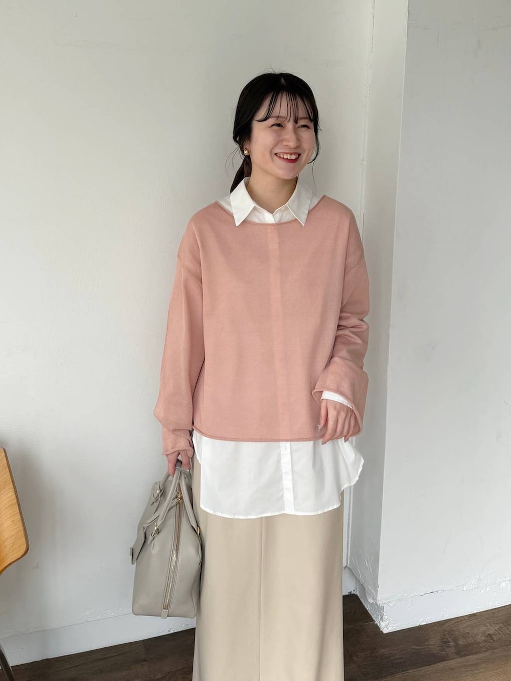 ピンク系のニット/セーター、ベージュ系のハンドバッグ、ホワイト系のサンダルを着用したレディースの春コーディネートの2枚目の写真