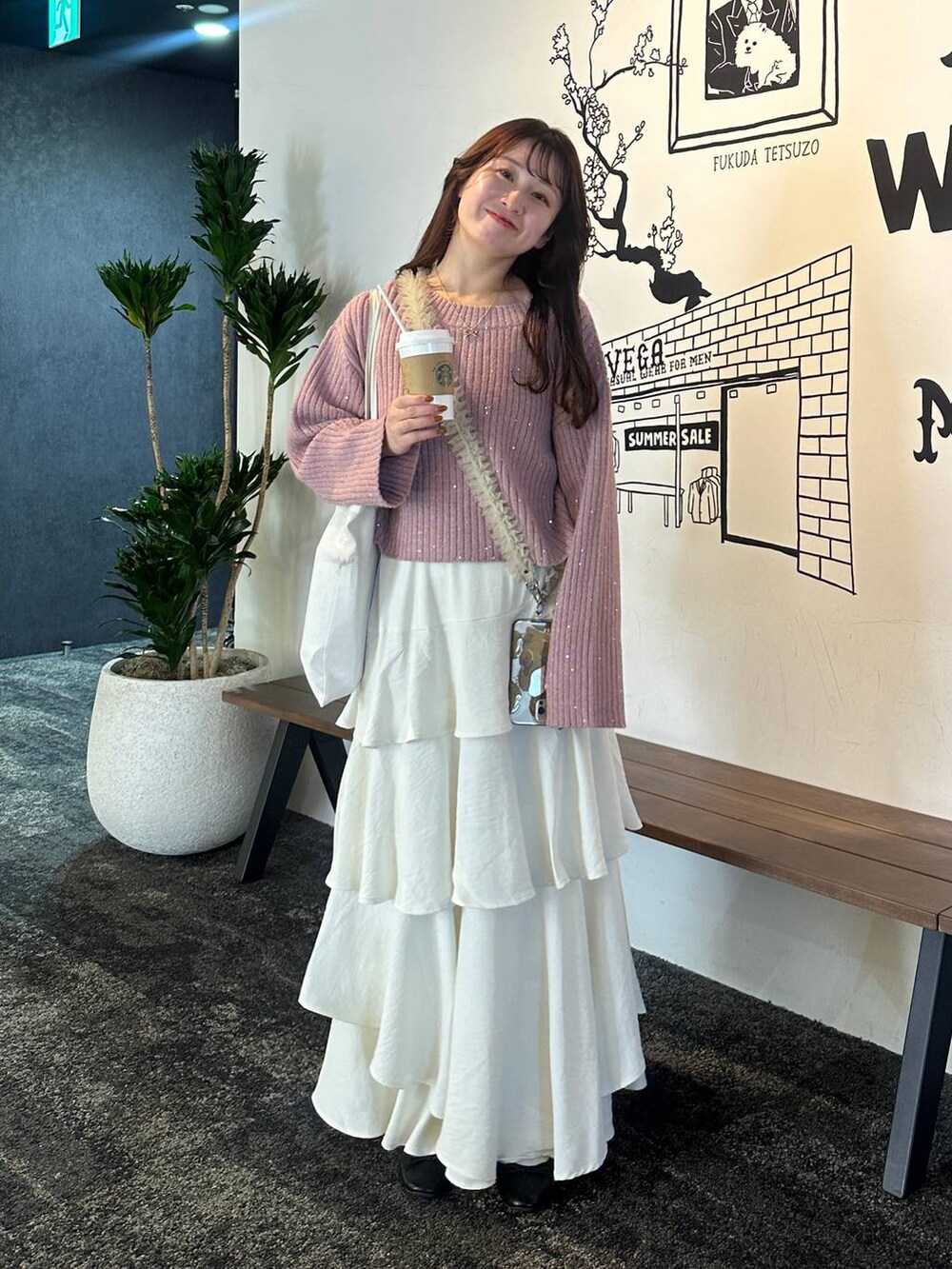 ホワイト系のスカート、ピンク系のニット/セーター、ベージュ系のスマホグッズを着用したレディースの秋コーディネートの5枚目の写真