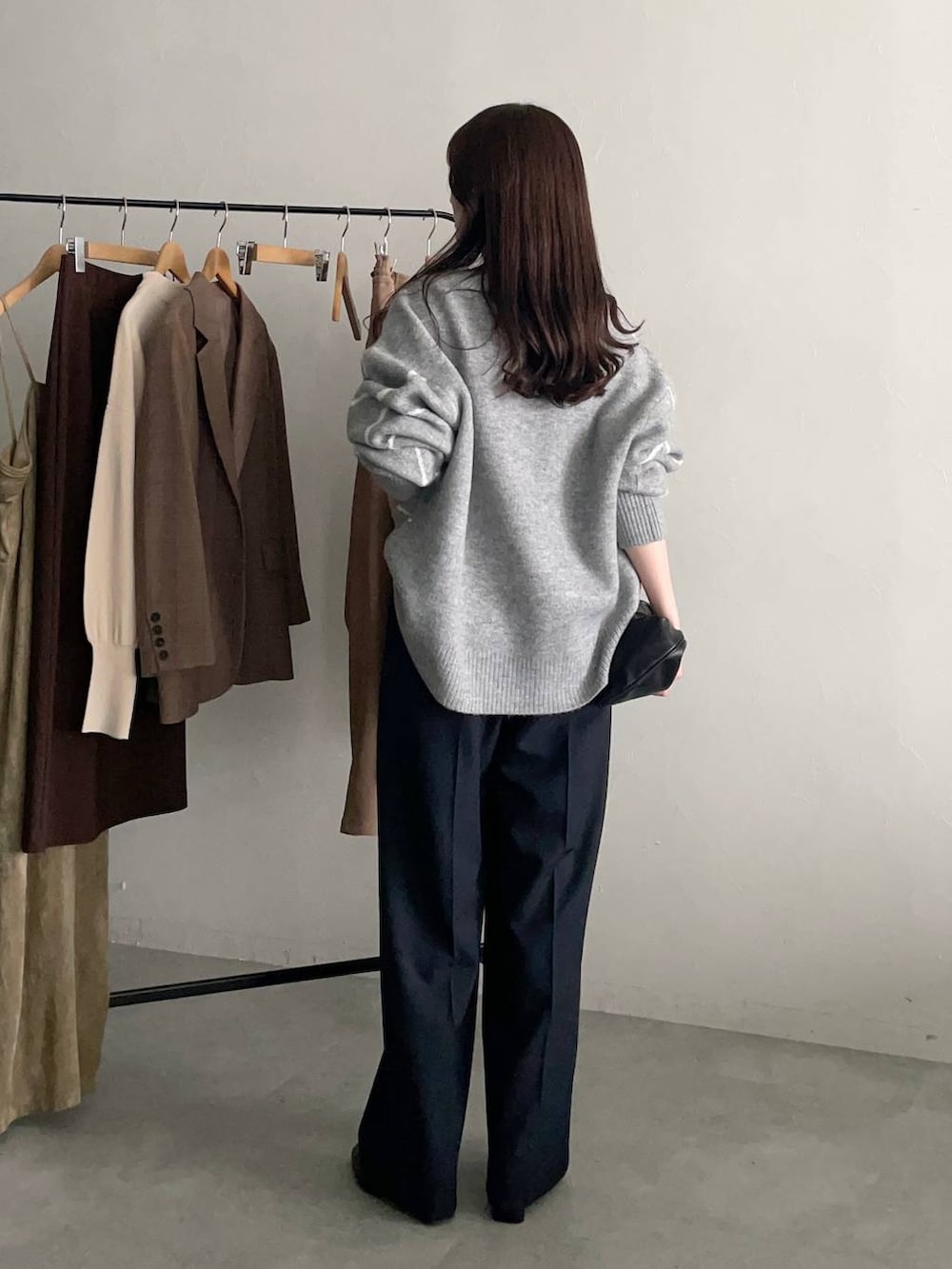 ブラック系のハンドバッグ、グレー系のニット/セーター、ブルー系のスラックスを着用したレディースの秋コーディネートの2枚目の写真