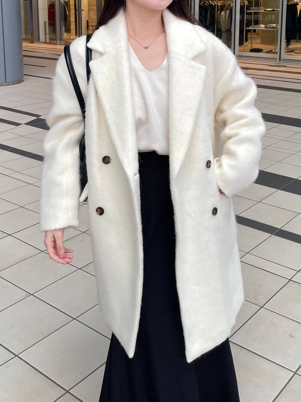 ホワイト系のニット/セーター、ホワイト系のチェスターコート、ブラック系のブーツを着用したレディースの秋コーディネートの4枚目の写真