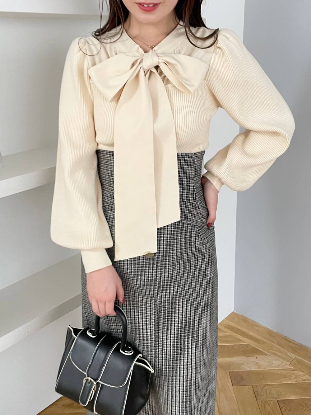 ブラウン系のチェスターコート、ブラック系のハンドバッグ、ブラック系のブーツを着用したレディースの秋コーディネートの6枚目の写真