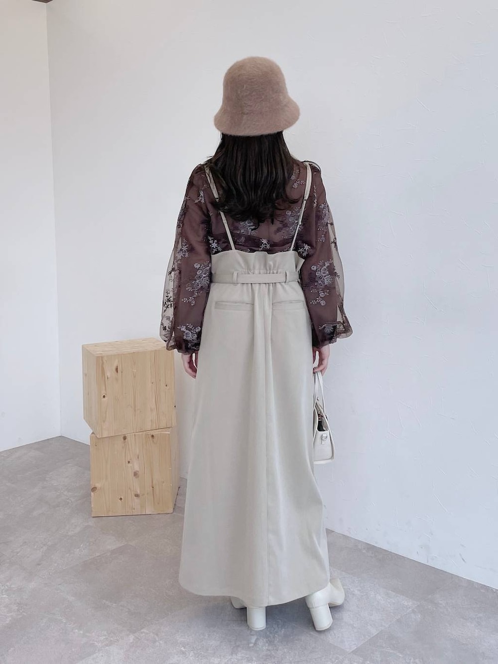 ホワイト系のボストンバッグ、ホワイト系のブーツ、ベージュ系のスカートを着用したレディースの夏コーディネートの2枚目の写真