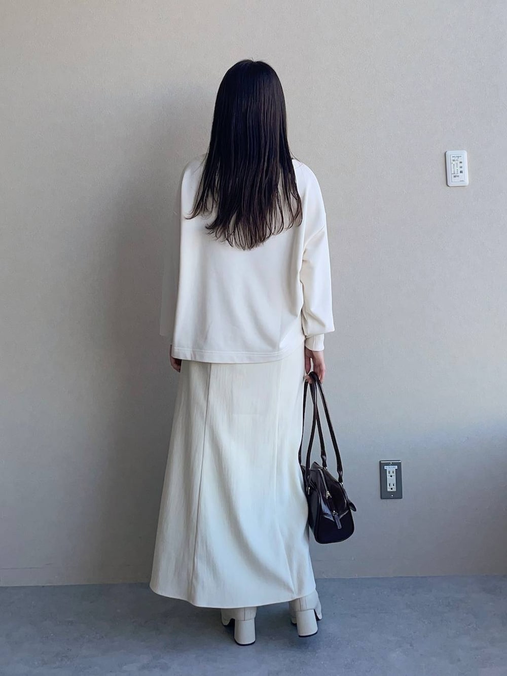 ホワイト系のブーツ、ブラウン系のハンドバッグ、ホワイト系のスウェットを着用したレディースの冬コーディネートの2枚目の写真