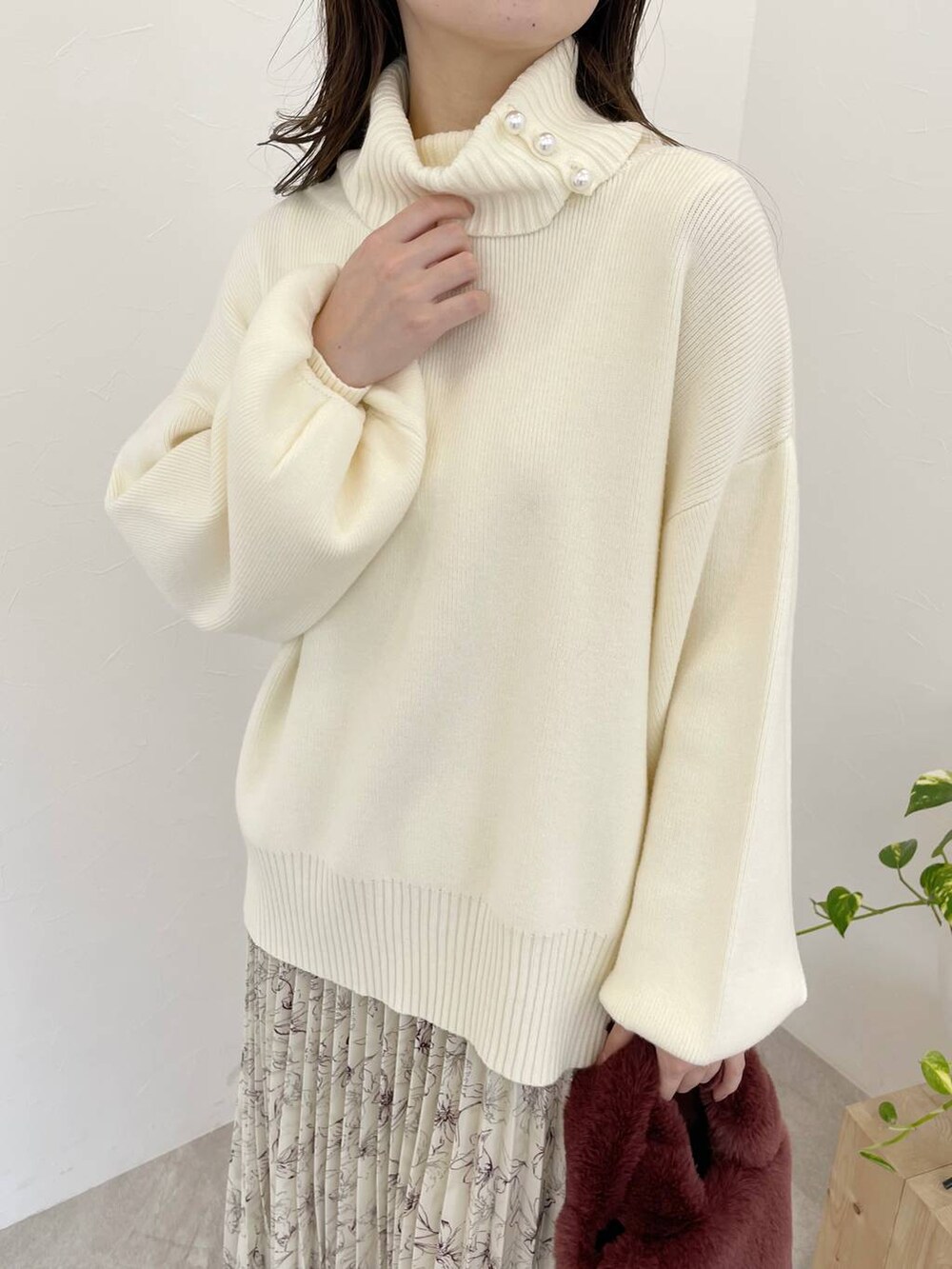 グレー系のブーツ、ピンク系のハンドバッグ、ホワイト系のスカートを着用したレディースの冬コーディネートの3枚目の写真