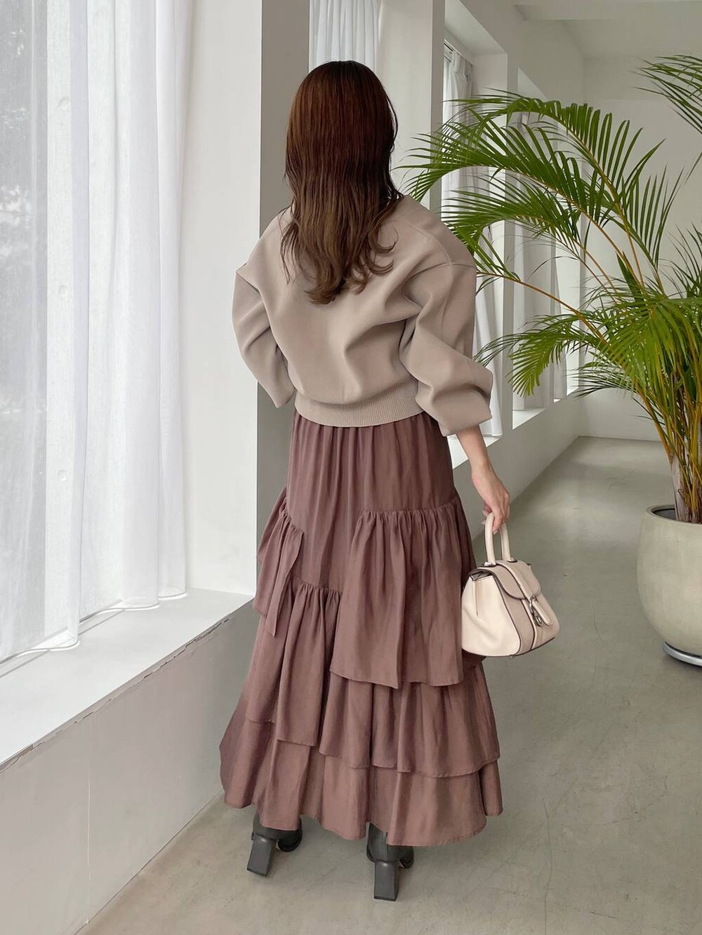 ホワイト系のハンドバッグ、グレー系のブーツ、ベージュ系のカーディガン/ボレロを着用したレディースの秋コーディネートの2枚目の写真