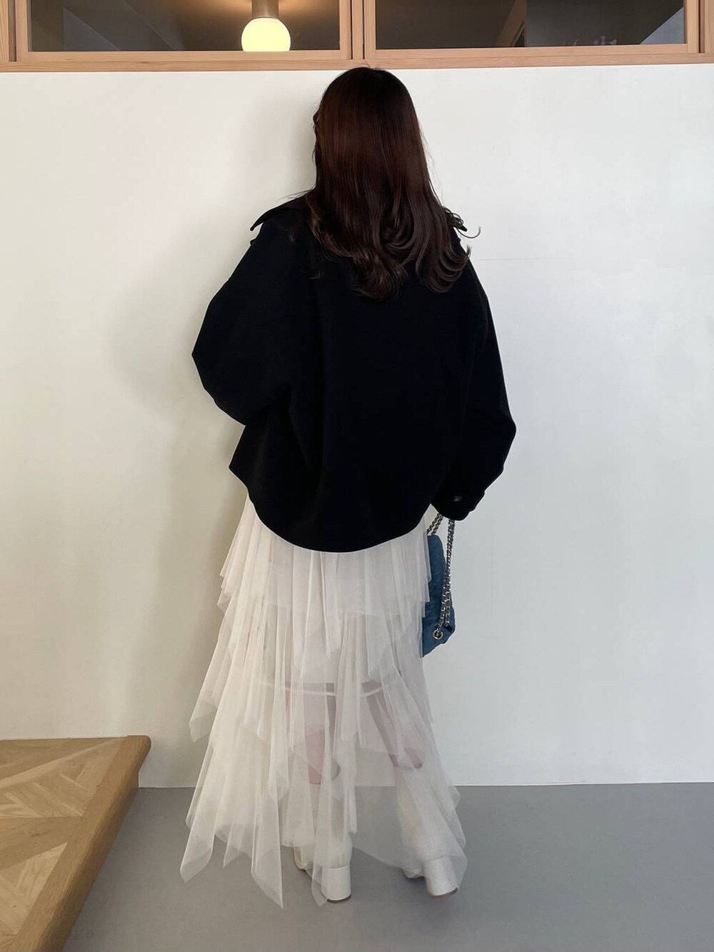 ブラック系のその他アウター、ホワイト系のブーツ、ホワイト系のスカートを着用したレディースの冬コーディネートの2枚目の写真