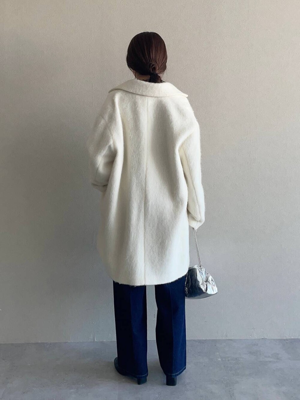 レッド系のニット/セーター、ブルー系のデニムパンツ、ホワイト系のチェスターコートを着用したレディースの冬コーディネートの2枚目の写真