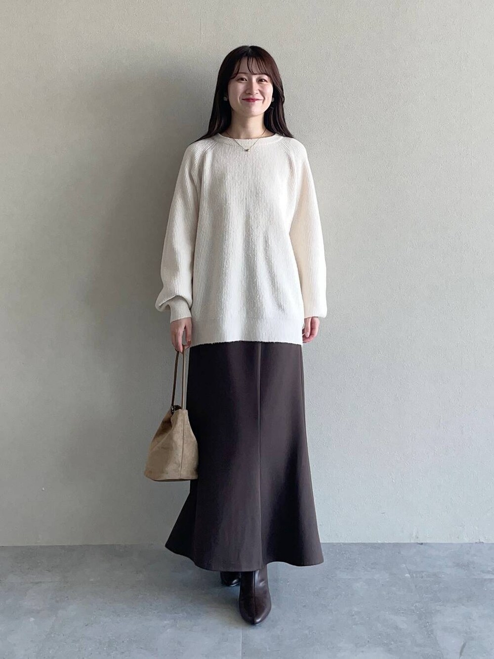 ブラウン系のスカート、ブラウン系のブルゾン、ホワイト系のニット/セーターを着用したレディースの秋コーディネートの3枚目の写真