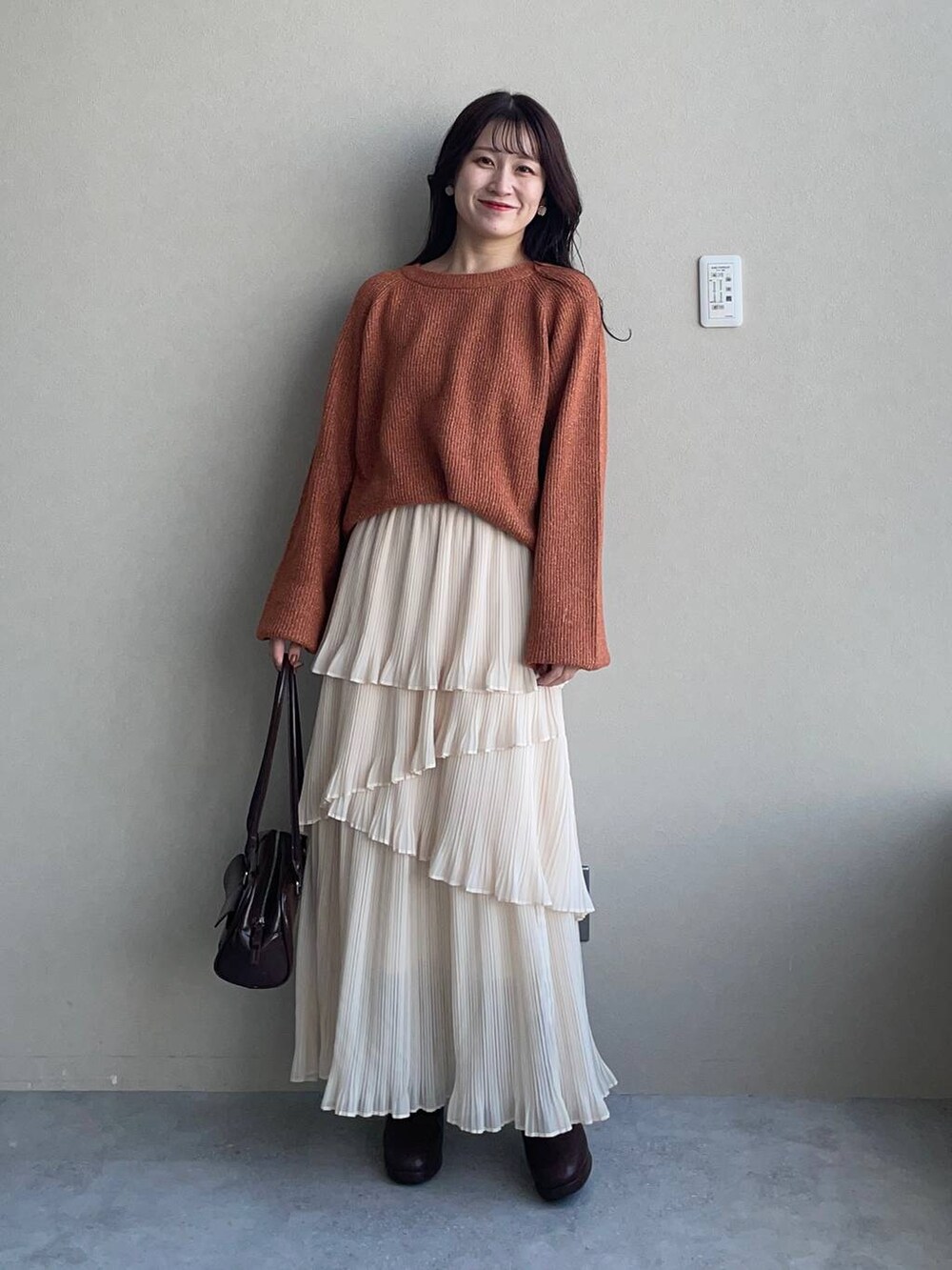 ベージュ系のピーコート、ブラウン系のブーツ、オレンジ系のニット/セーターを着用したレディースの冬コーディネートの3枚目の写真