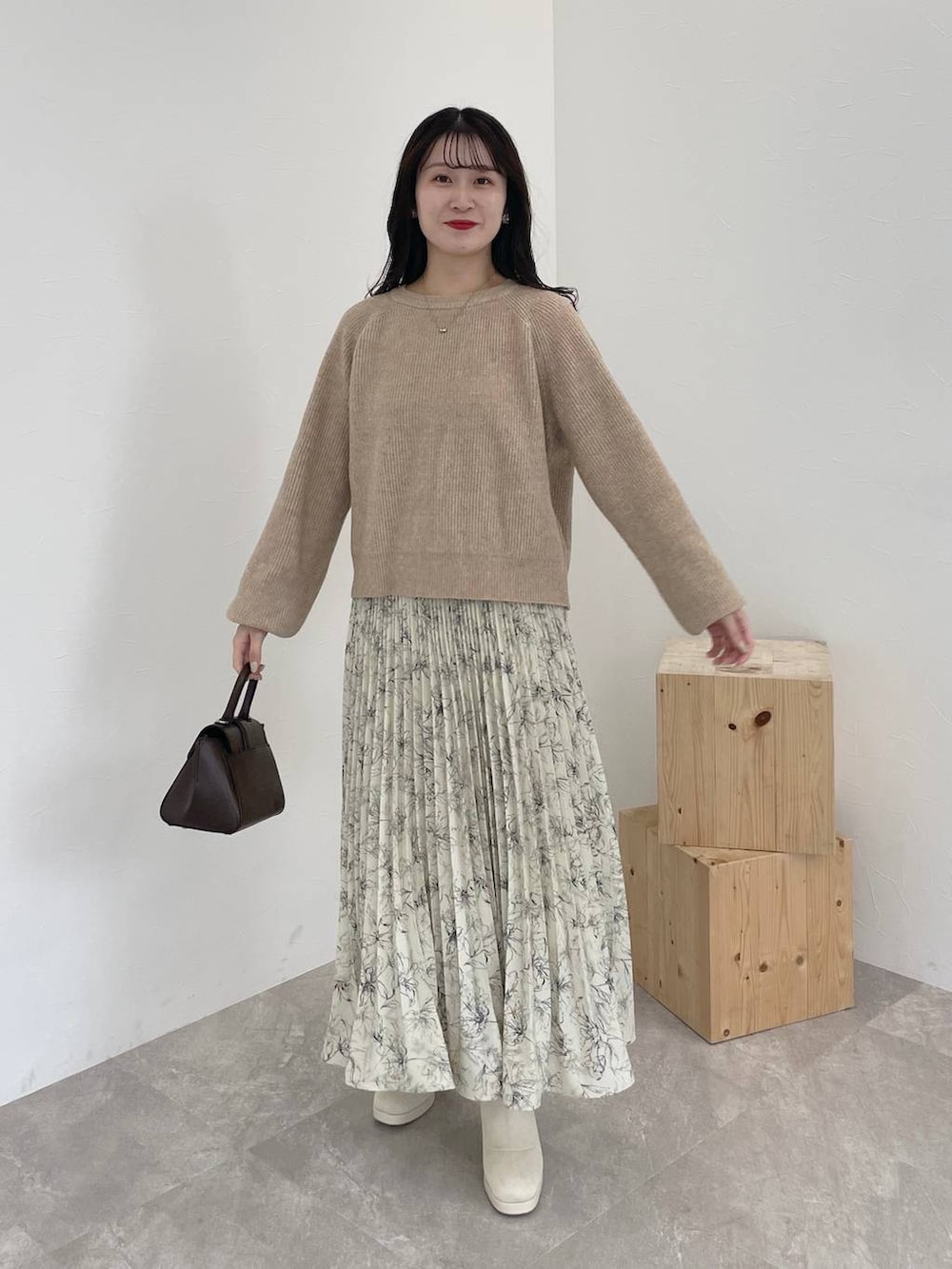 ベージュ系のニット/セーター、ブラウン系のチェスターコート、ブラウン系のハンドバッグを着用したレディースの秋コーディネートの4枚目の写真