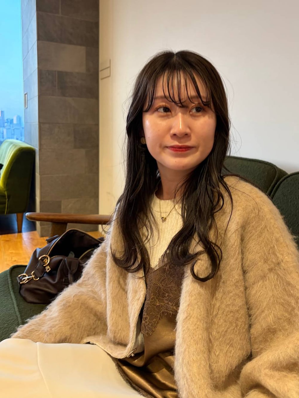 ブラック系のボストンバッグ、ブラウン系のキャミソール、ベージュ系のスマホグッズを着用したレディースの春コーディネートの3枚目の写真