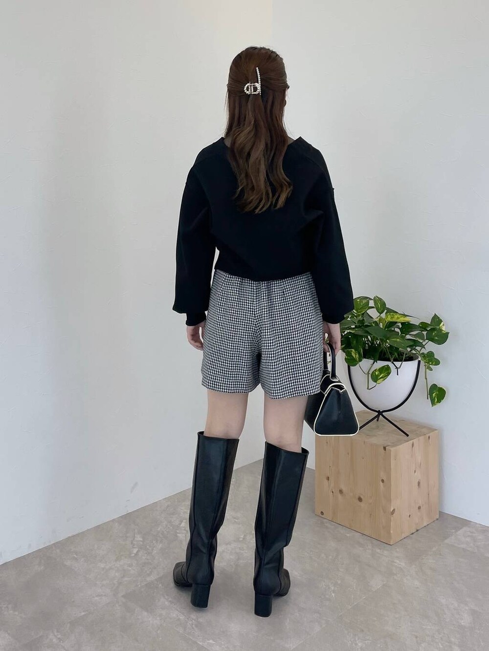 ブラック系のハンドバッグ、ブラック系のブーツ、グレー系のTシャツ/カットソーを着用したレディースの秋コーディネートの2枚目の写真