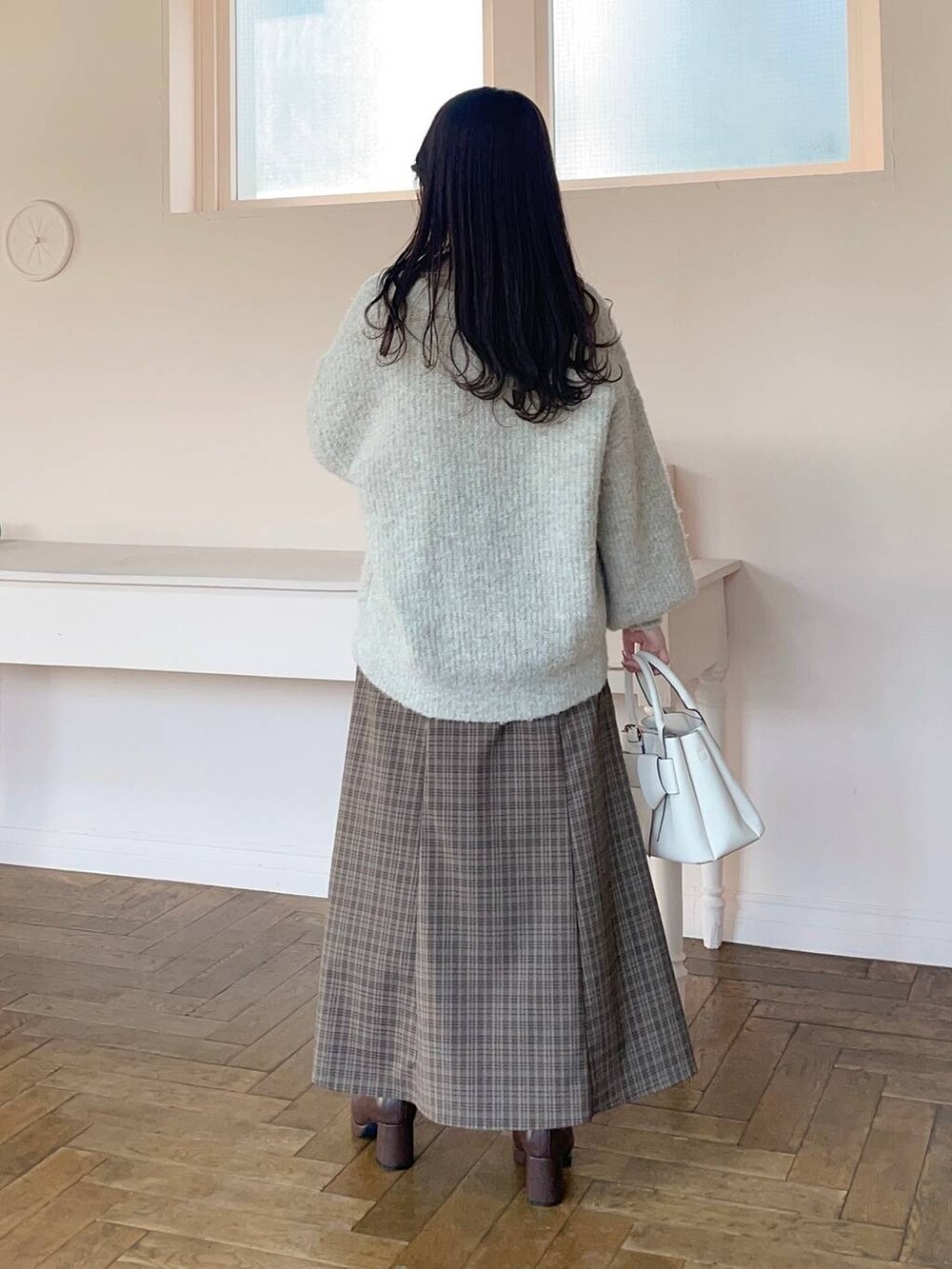 ブラウン系のブーツ、ブラウン系のスカート、ベージュ系のTシャツ/カットソーを着用したレディースの冬コーディネートの2枚目の写真