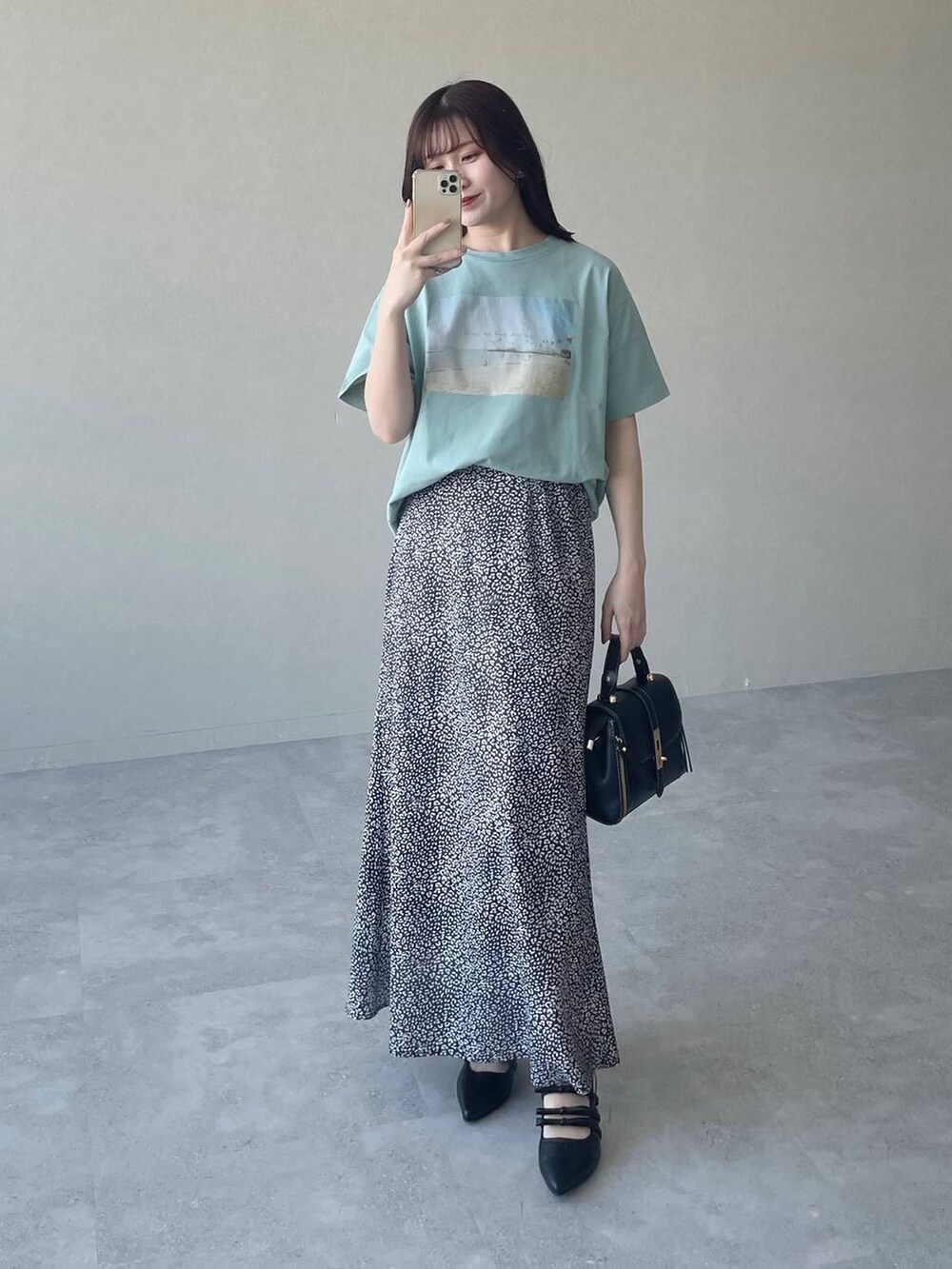 ブラック系のスカート、ブラック系のパンプス、グリーン系のTシャツ/カットソーを着用したレディースの春コーディネートの4枚目の写真