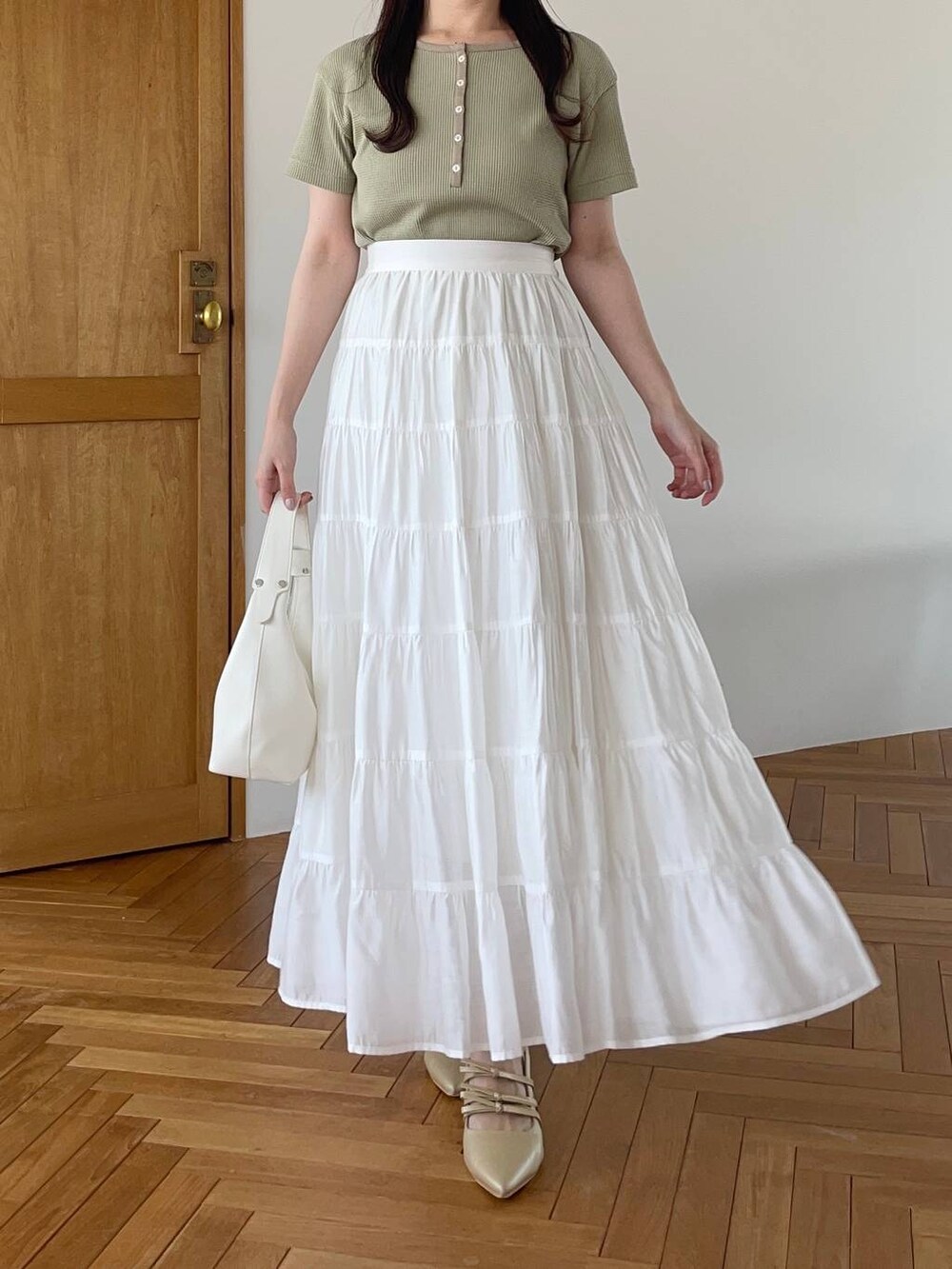 ホワイト系のショルダーバッグ、ゴールド系のパンプス、グリーン系のTシャツ/カットソーを着用したレディースの夏コーディネートの4枚目の写真